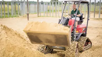 Zookeeper in a digger in the sand paddock at centre for elephant care