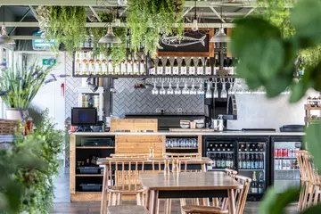 The inside decor of Viewpoint restaurant at Whipsnade Zoo, showing tables with chairs, fridges full of drinks, and green foliage