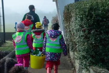 Group of children walking carrying a bucket