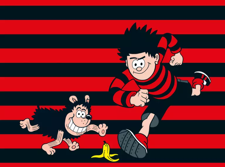 Dennis Menace and Gnasher on a red and black background, running towards a banana skin on the floor 