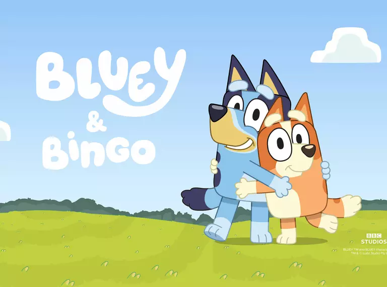 Characters Bluey and Bingo stand on a green meadow with blue sky and clouds above them and their character titles to the left of the sky