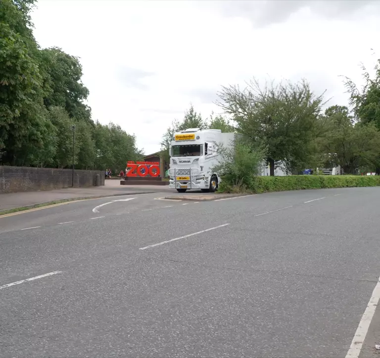 Specialist transport lorry carrying Karishma the elephant passing the Whipsnade Zoo sign